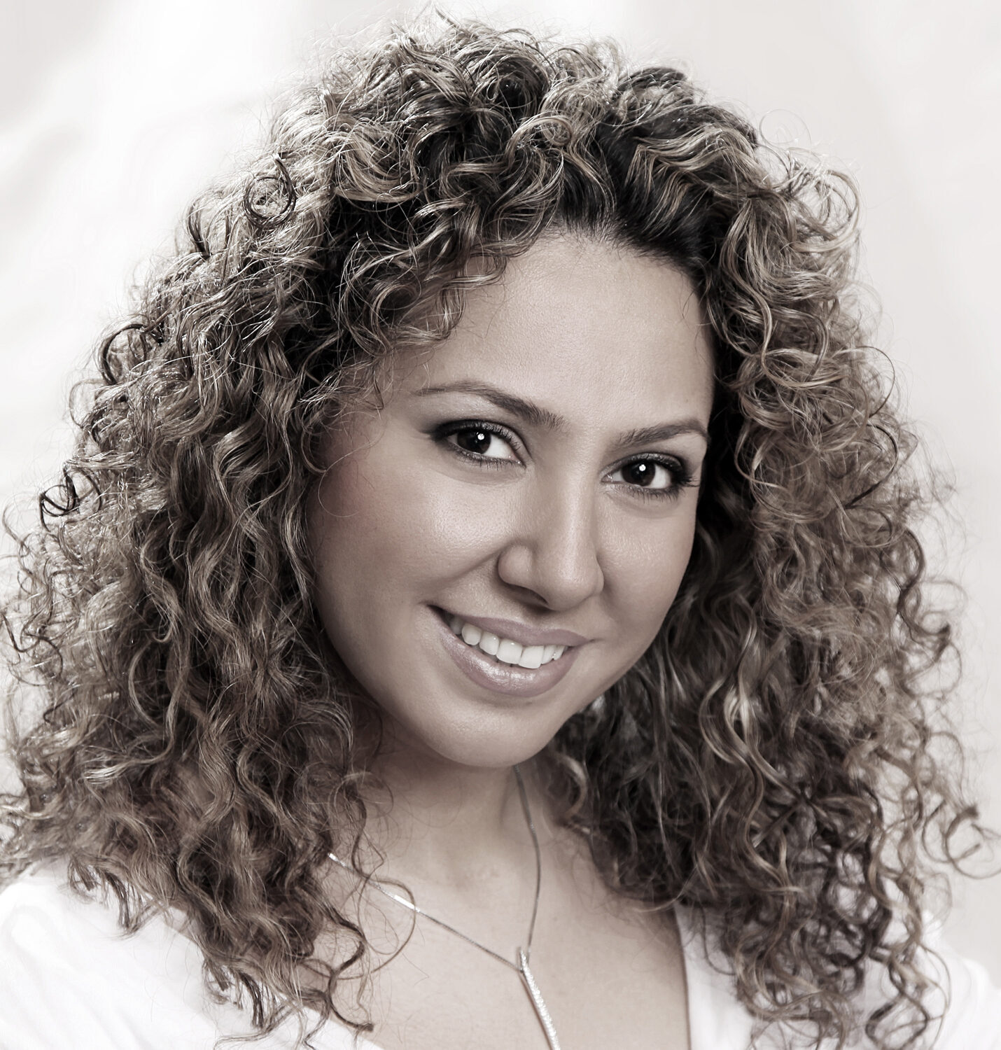 Curly-haired woman grinning for the camera.