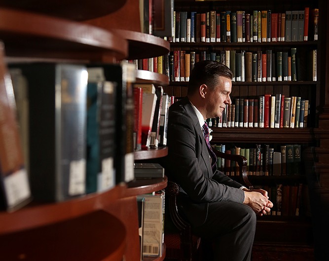 A man sitting in a chair surrounded by books in a library.