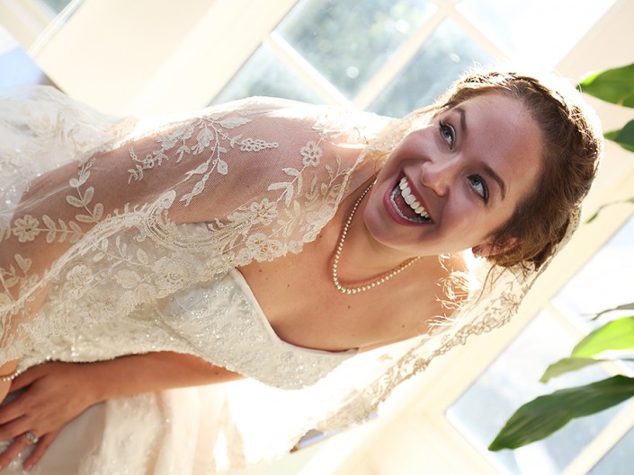 A woman in a wedding dress, radiating joy with a captivating smile, exudes happiness on her special day.