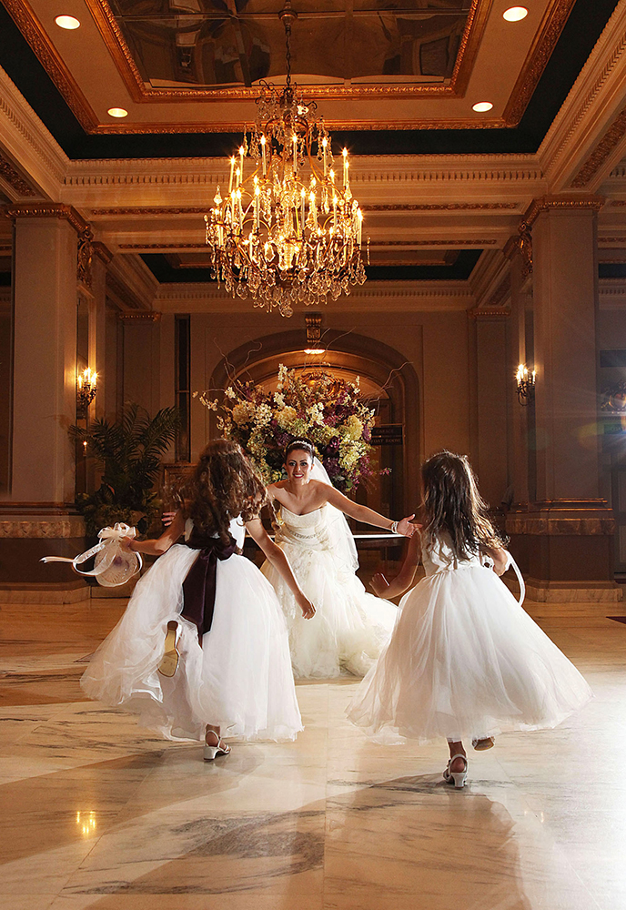 Bride and bridesmaids dancing joyfully in a ballroom.