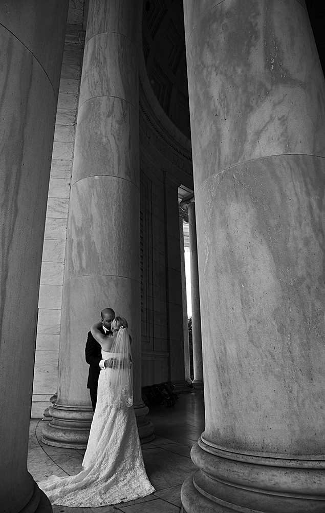 Newlyweds posing in front of elegant columns on their special day.