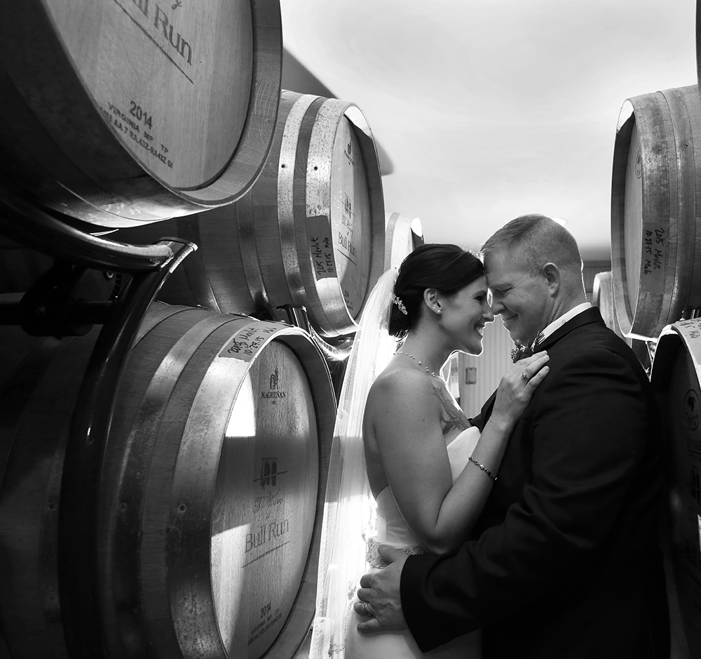 Couple by wine barrels, radiating joy and love at winery