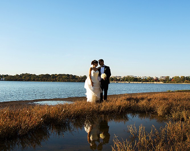 Newlyweds standing in shallow water near the shore on their wedding day.