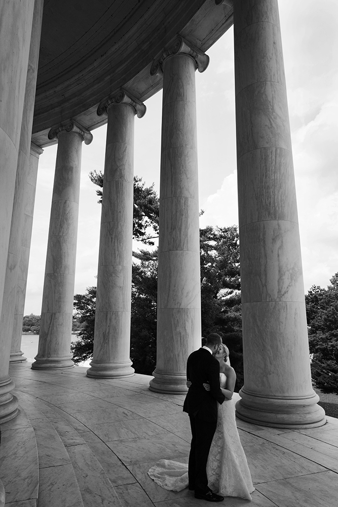 A couple shares a tender kiss in front of the Jefferson Memorial, celebrating their union on their wedding day.