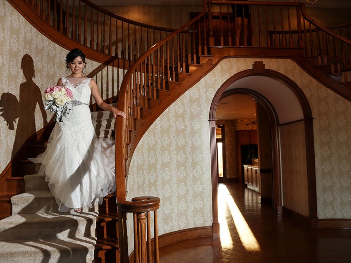 Beautiful bride in wedding gown descending stairs with grace and excitement.