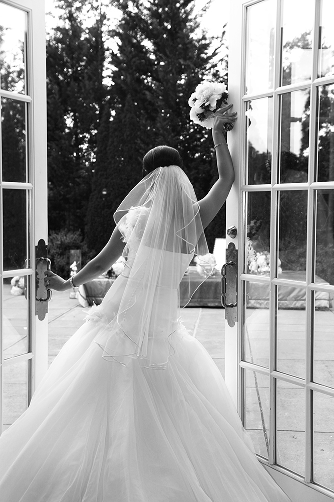 Beautiful bride poised in front of an open door, ready for a new journey.