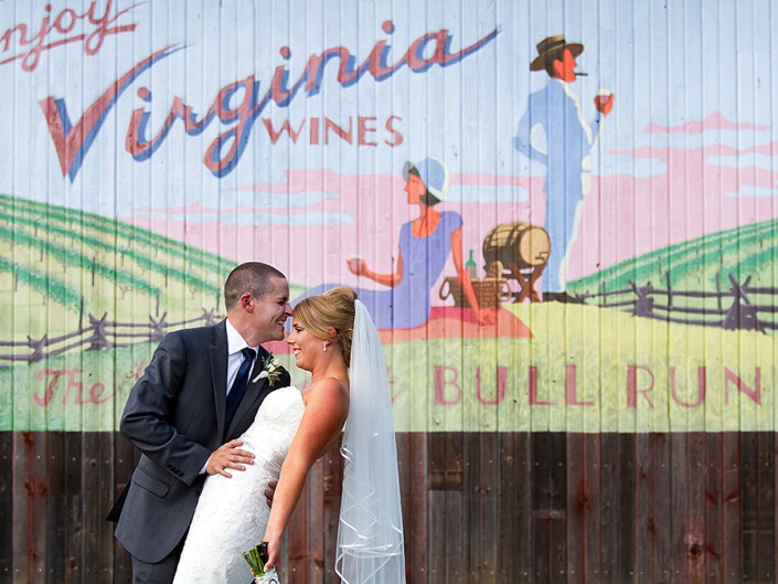 Newlyweds share tender kiss by 'Virginia Wines' sign, joyous celebration