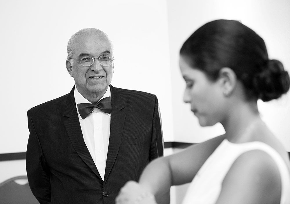 A man in a sleek tuxedo gazes at a woman in a stunning wedding dress, capturing a moment of elegance and anticipation.