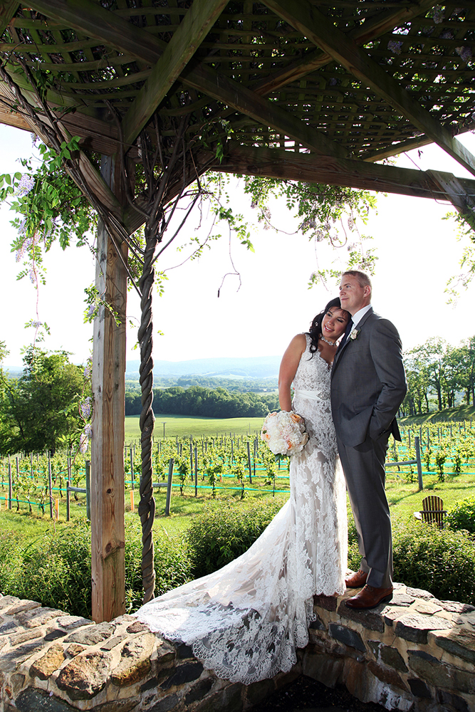 Bride and groom smile beneath pergola gazebo, capturing cherished moment on their special day