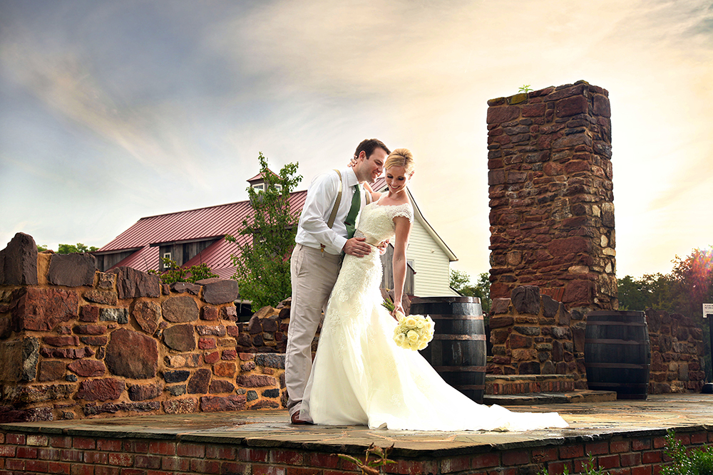 Newlyweds share a kiss in front of a brick building on their special day.