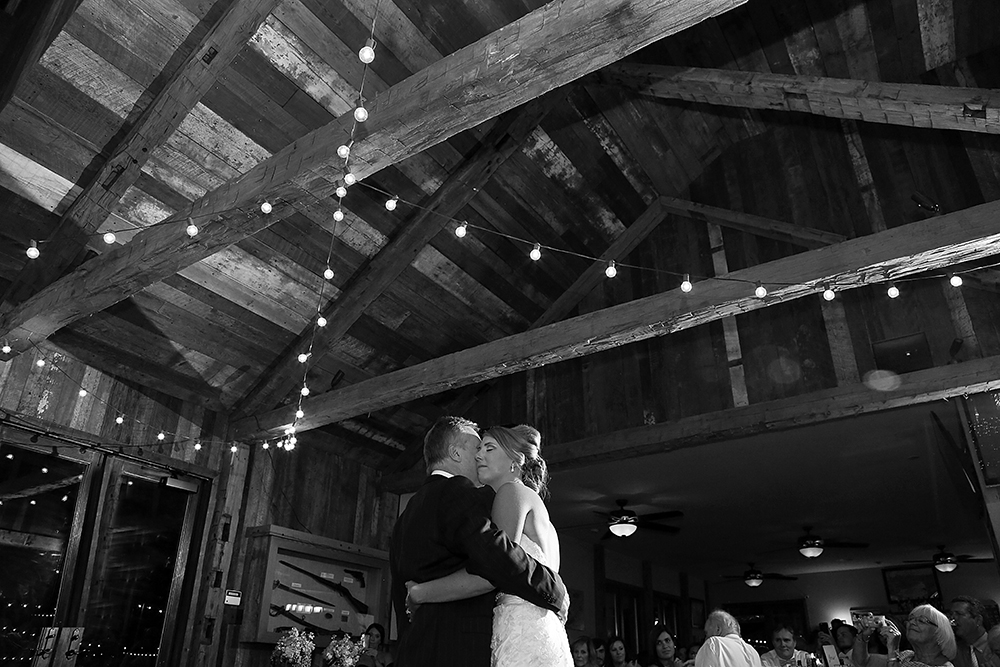 A newlywed couple gracefully dances, celebrating their union, surrounded by loved ones at their wedding reception.