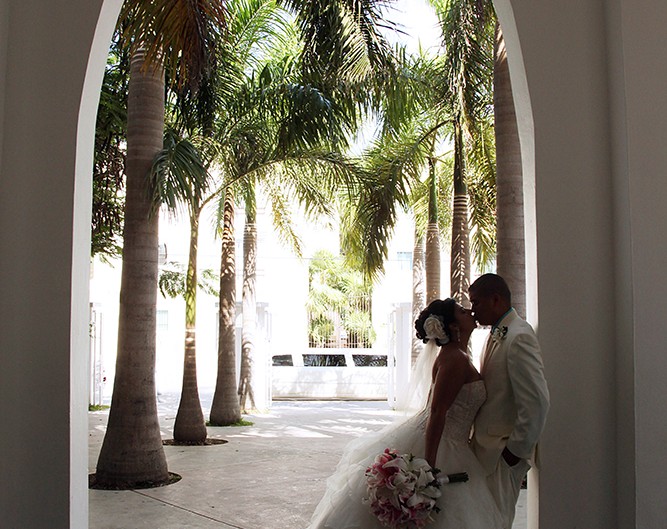 Newlyweds pose before palm tree, capturing timeless wedding moment