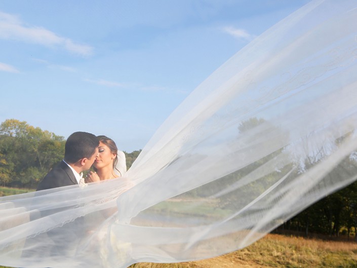 Bride and groom's tender kiss under a veil.