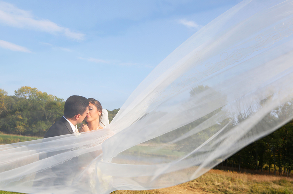 Bride and groom's tender kiss under a veil.