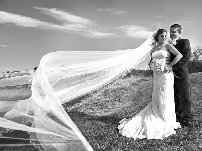 Couple with fluttering wedding veil, joyful moment.