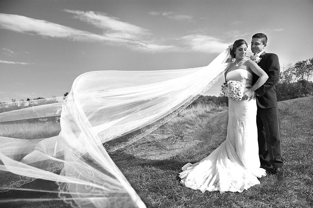 Couple with fluttering wedding veil, joyful moment.