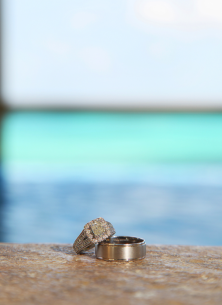 Two wedding rings resting on a poolside ledge, symbolizing eternal love and commitment.