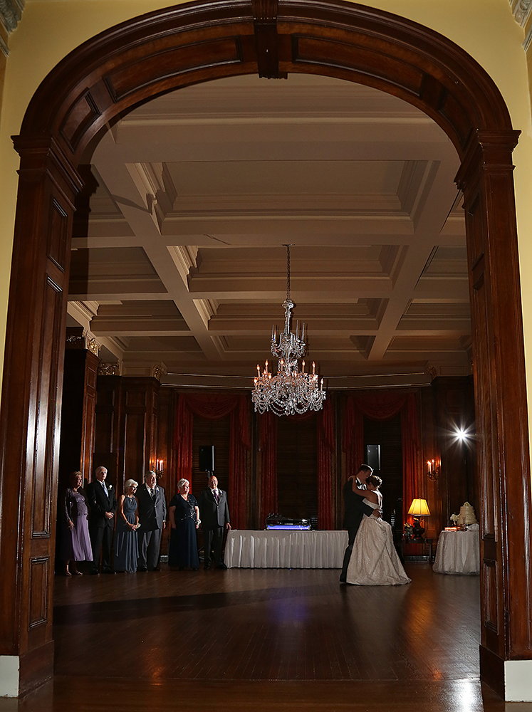A wedding couple gracefully dancing in a spacious room, radiating joy and love on their special day.