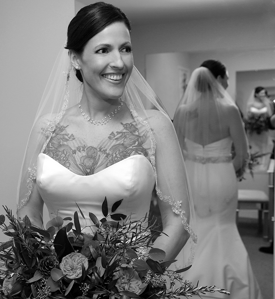 Bride in wedding dress, smiling joyfully at the camera on her special day.
