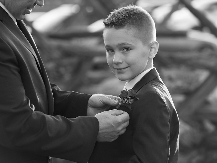 Young boy assisting father in tying a tie, showcasing their generational bond.