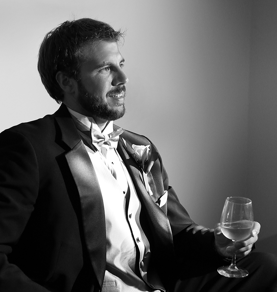 Gentleman in formal attire holding a wine glass with elegance.