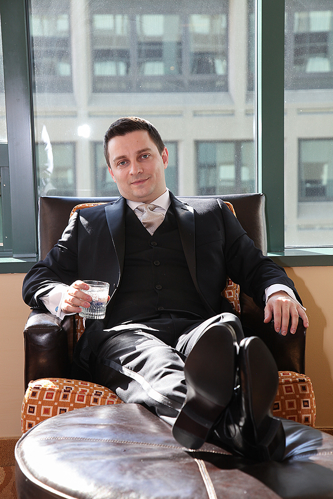 A man seated in a chair holding a glass of water.