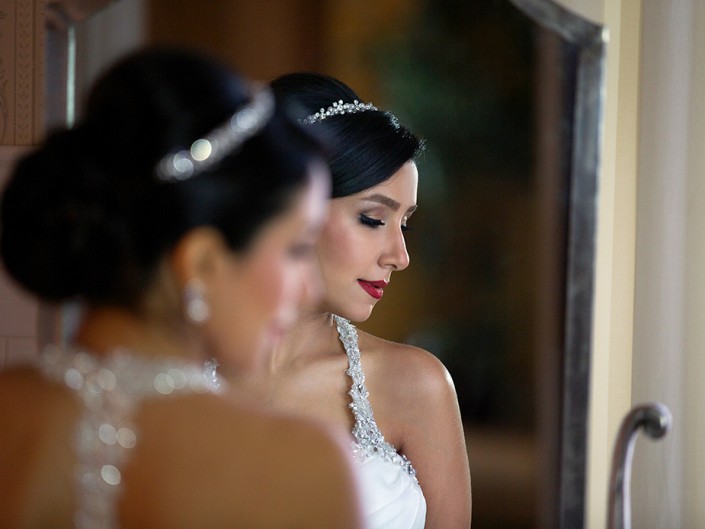 A bride admiring her reflection in the mirror, captivated by her elegant wedding gown.