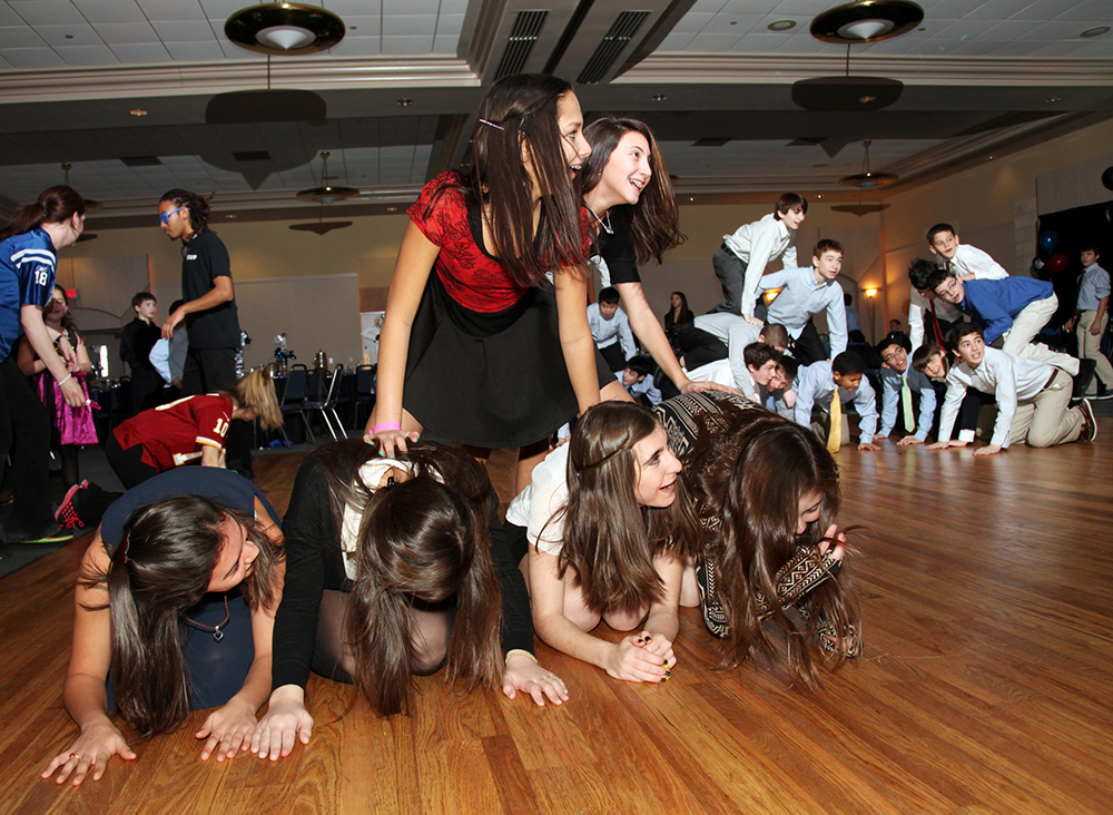 A group of young girls sitting on the floor, actively engaged in an activity.