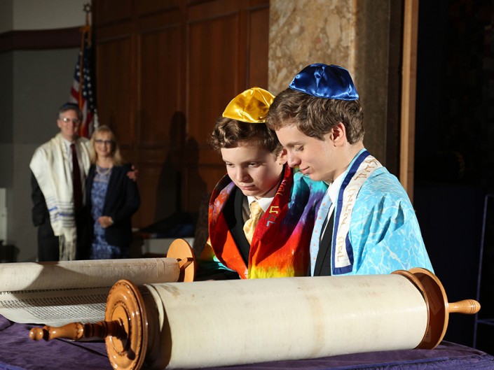 Two young men in traditional attire examining a scroll, showcasing cultural heritage and curiosity.