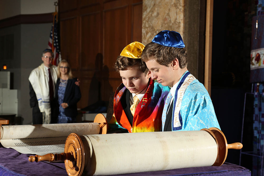 Two young men in traditional attire examining a scroll, showcasing cultural heritage and curiosity.