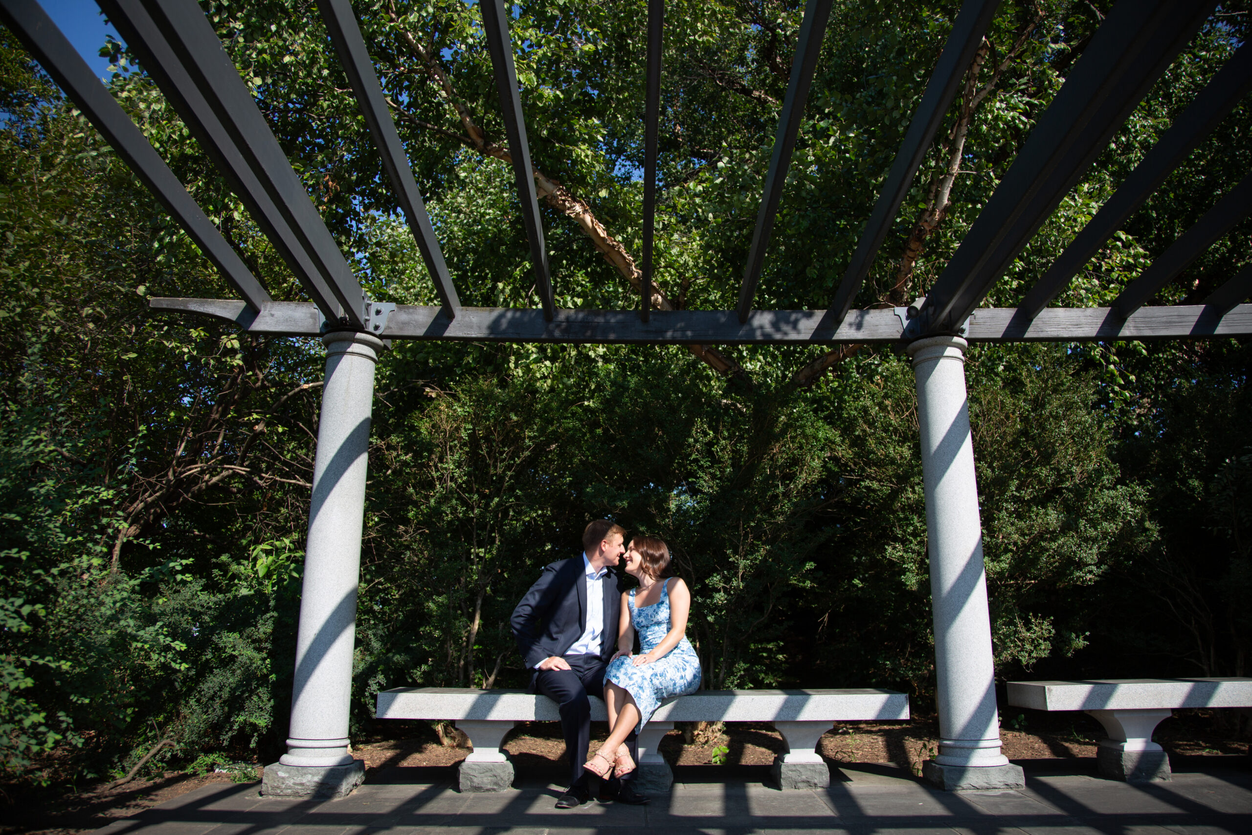 Couple sharing a romantic moment on a bench under trees