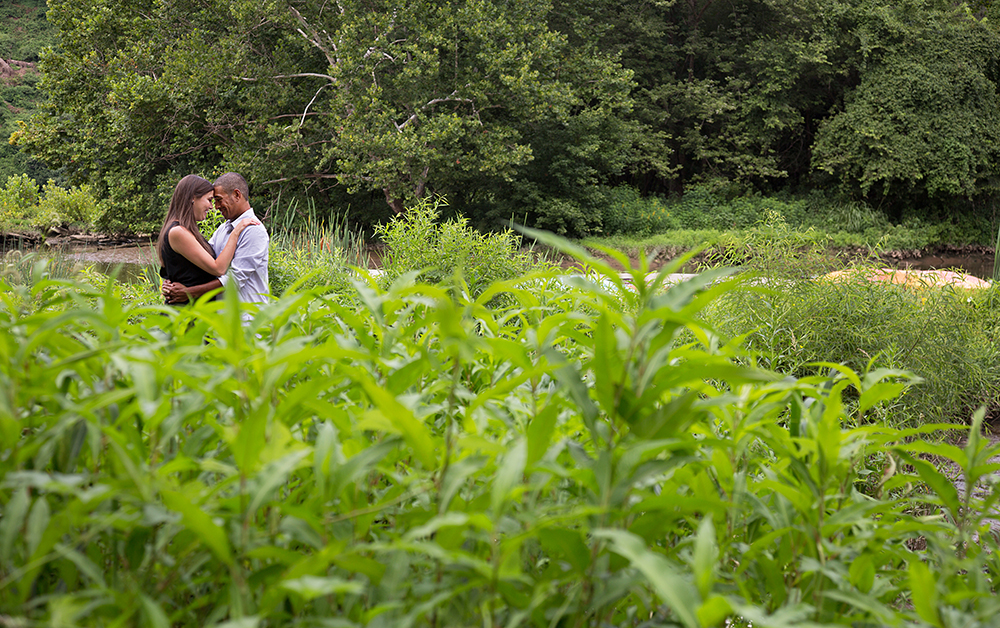 Couple standing in tall grass field.