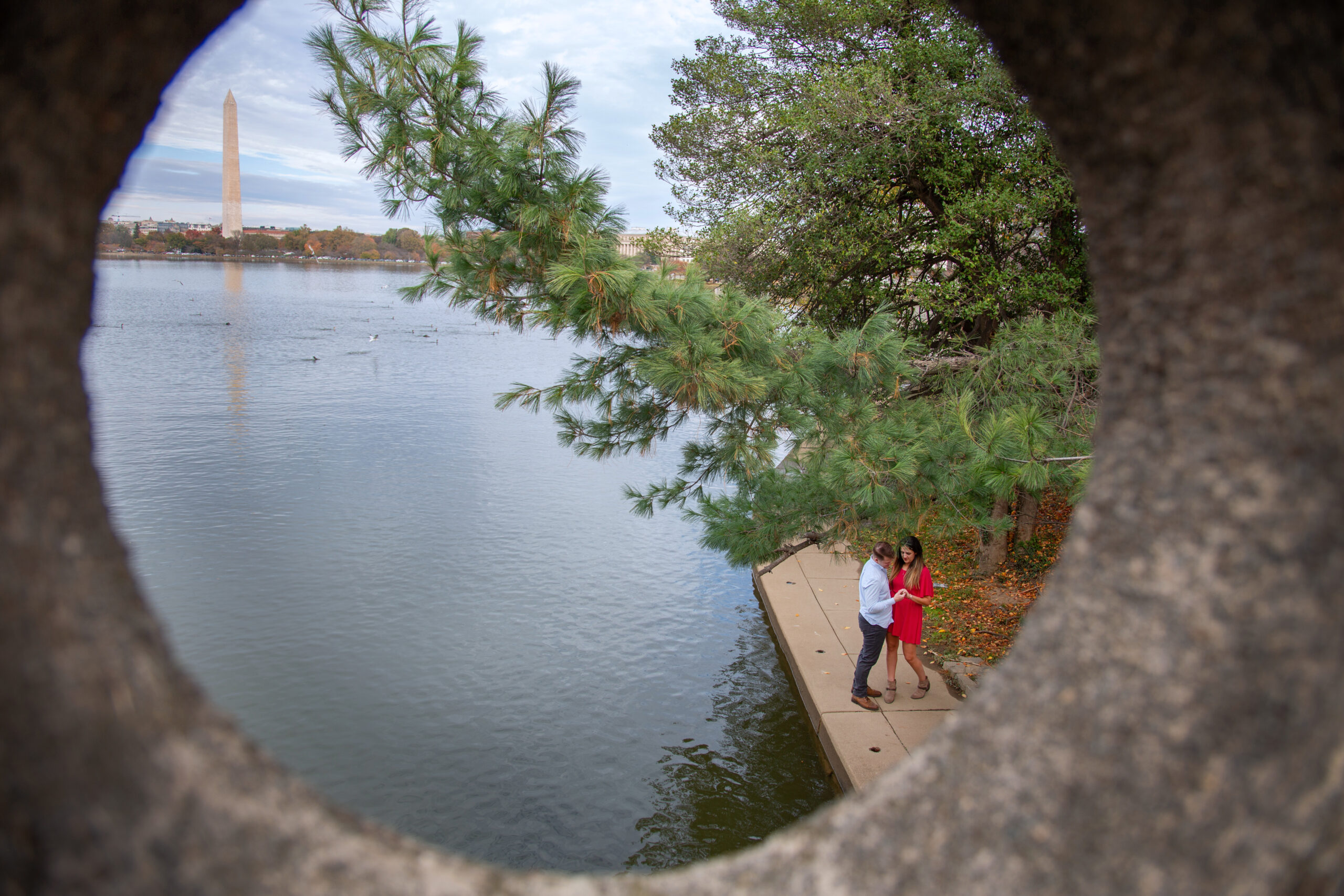 Engaged couple and the DC monument showing from one of the holes of the bridge. Tidal Basin Washington DC
