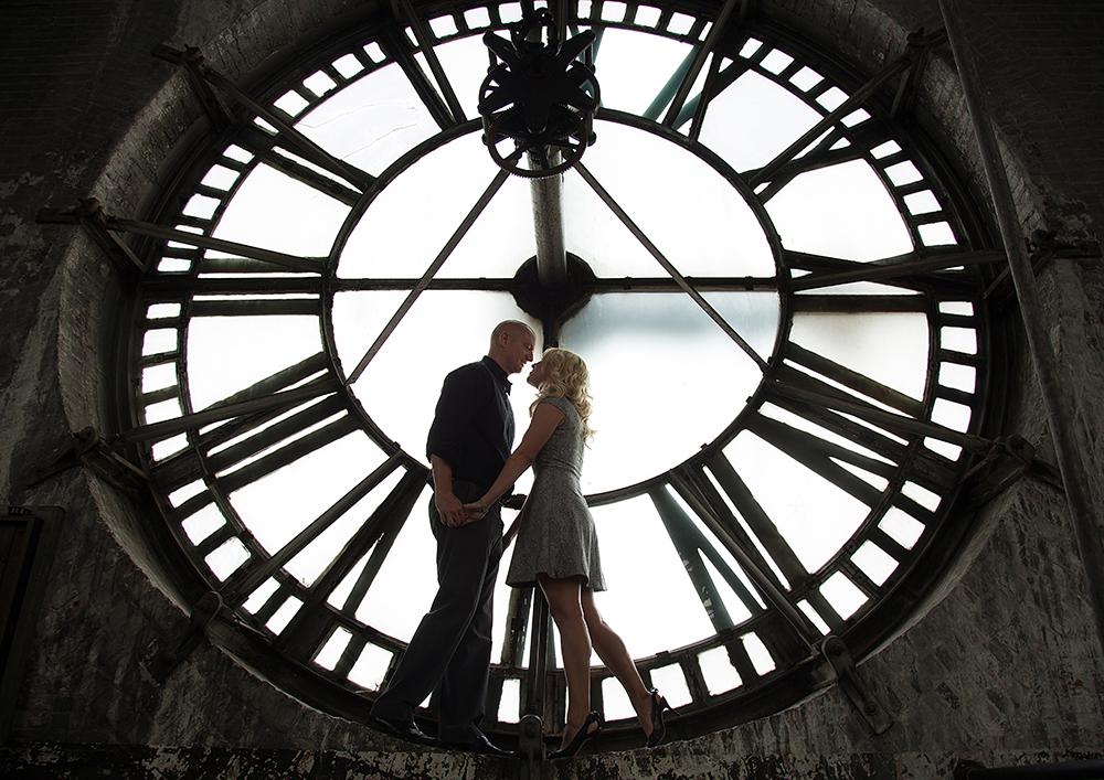 Couple standing in front of a clock.