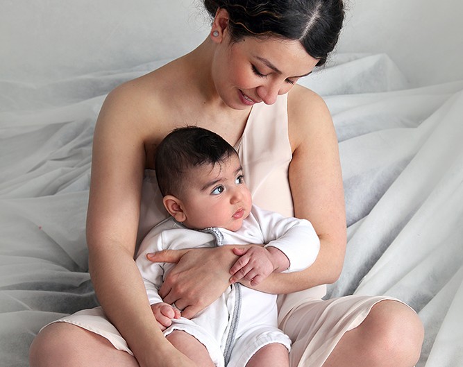 Affectionate mother cradles baby with love on cozy bed