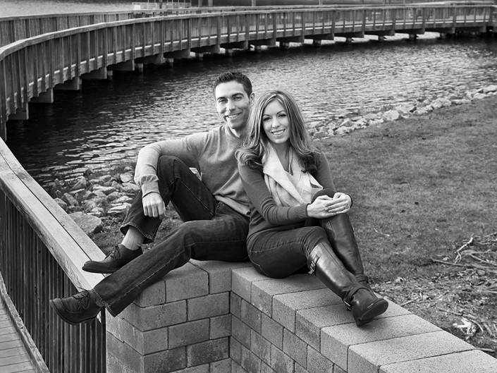 A happy couple enjoying a scenic river view from a wall.