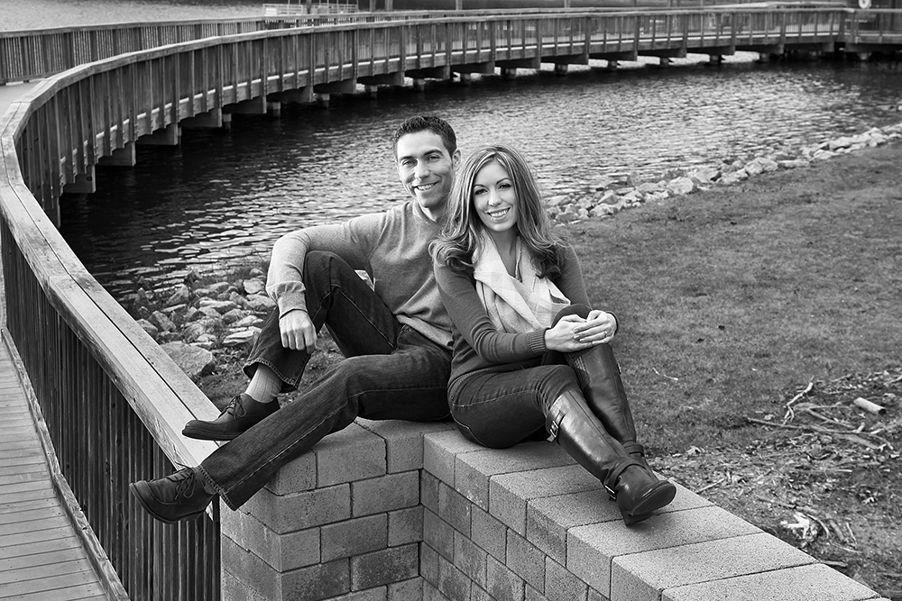 A happy couple enjoying a scenic river view from a wall.