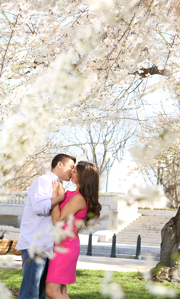 A couple sharing a passionate kiss beneath the shade of a tree, surrounded by the tranquil beauty of nature.