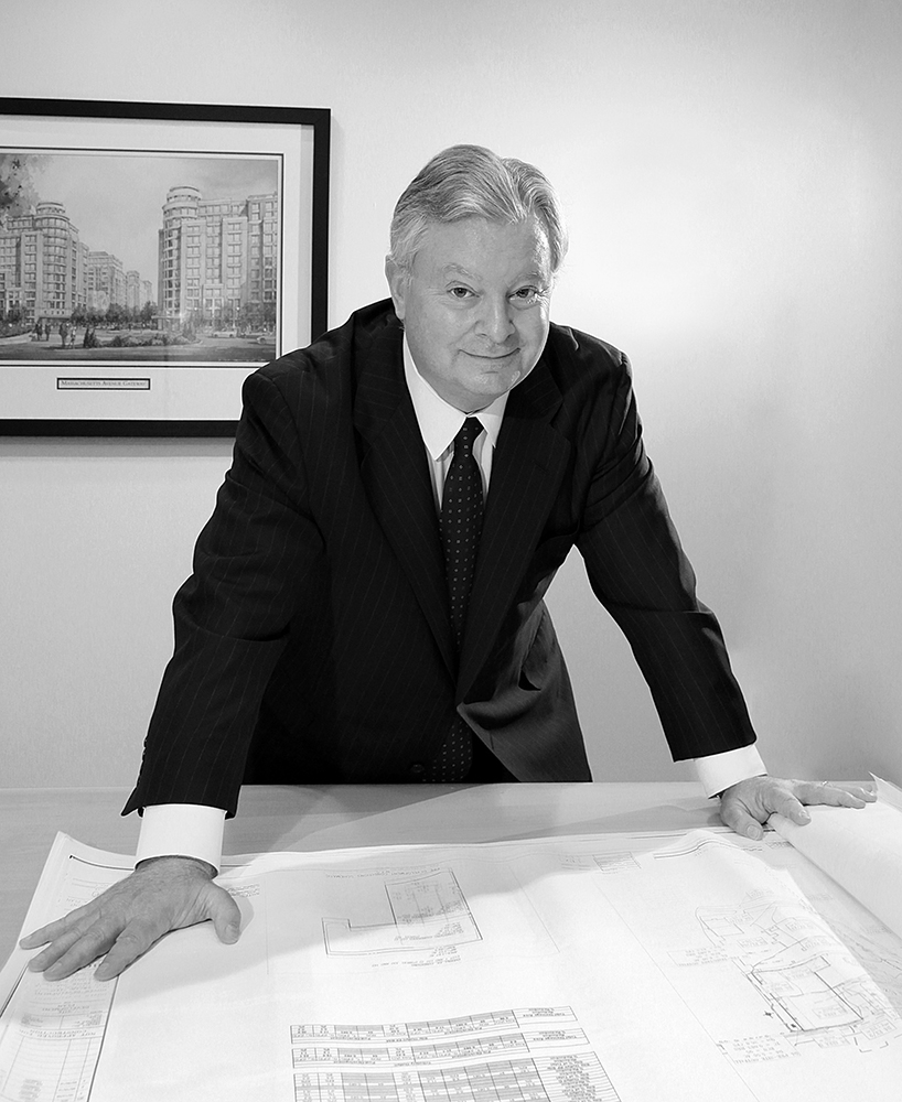 Businessman reviewing blueprints on table.