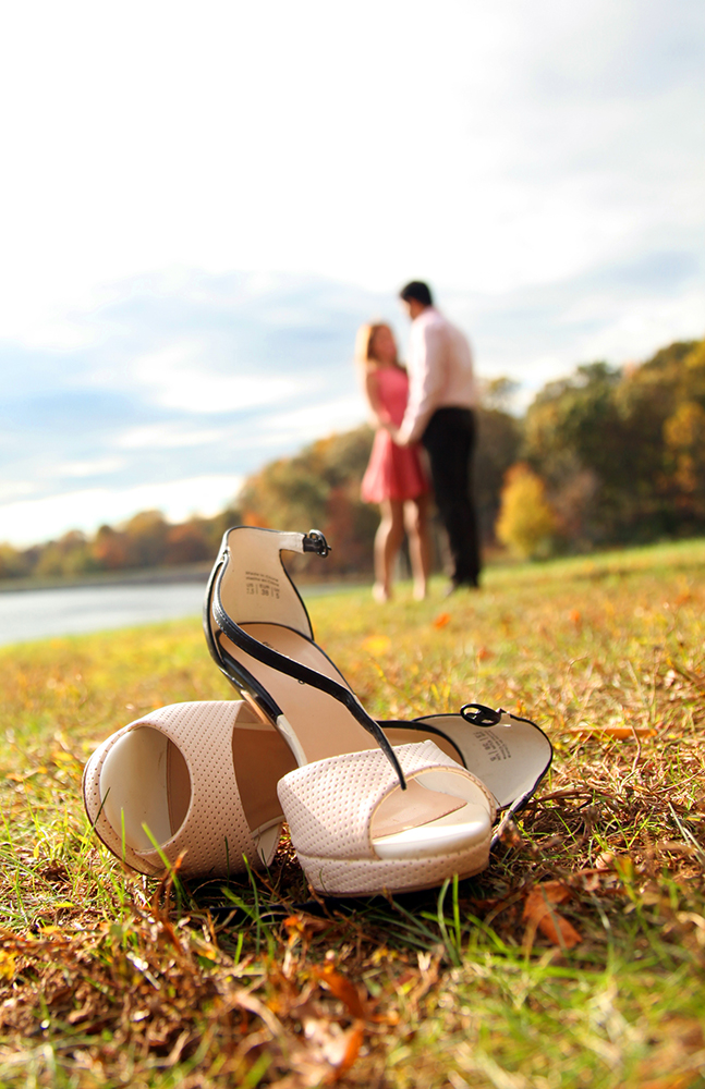 A man and woman standing beside a pair of shoes on the ground.