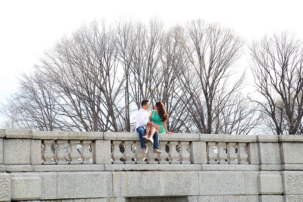 A couple sitting on a bridge, enjoying a serene moment together, surrounded by nature's beauty.
