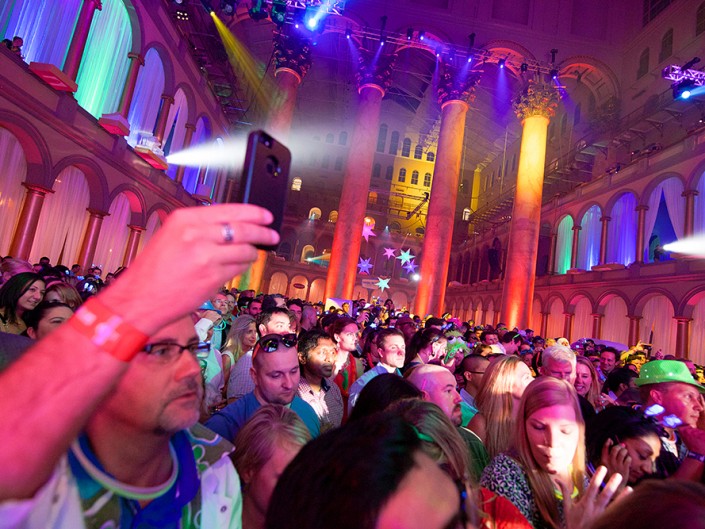 Vibrant crowd in spacious hall illuminated by colorful lights. National Building Museum, Washington DC