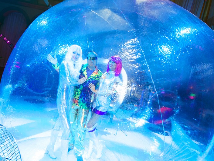Three people having fun inside a bubble ball at a lively party.
