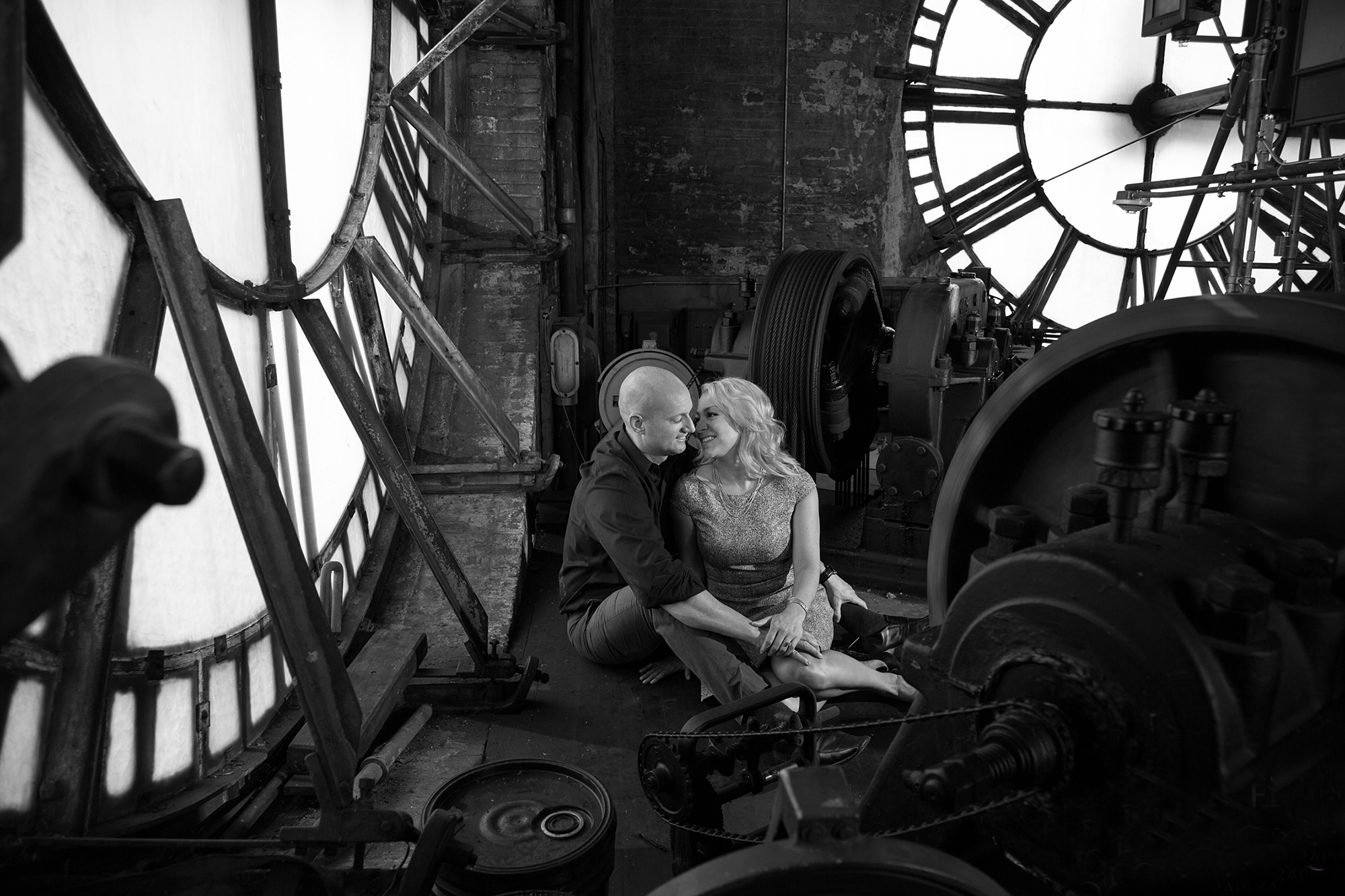 Couple sitting together in front of a clock, enjoying each other's company.
