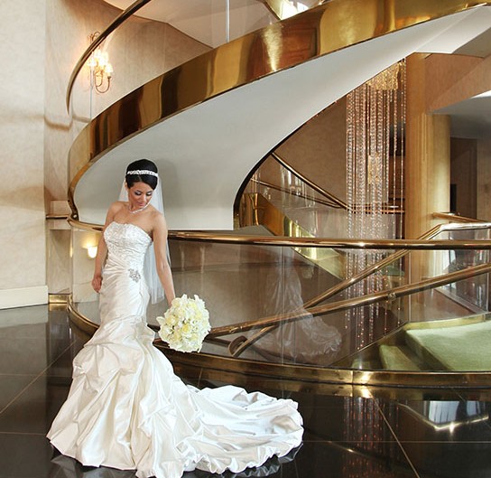 Bride on spiral staircase, radiating elegance.