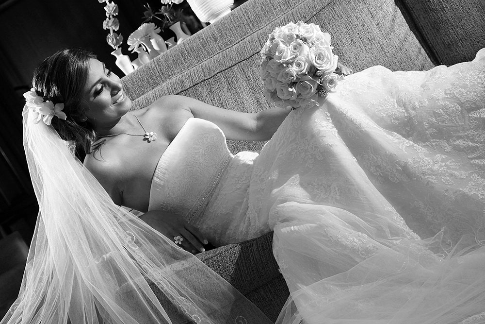 Elegant bride in a wedding dress reclining on a couch, radiating beauty and grace.