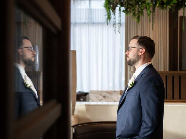 Groom admiring his reflection, excited for his wedding day.