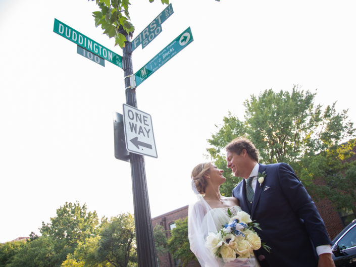 Couple sharing a tender moment under a street sign on their wedding day