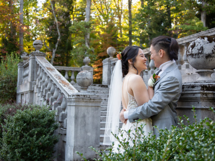 A bride and groom share a loving embrace in front of a majestic stone staircase, symbolizing their unbreakable bond and the commencement of their lifelong journey together.