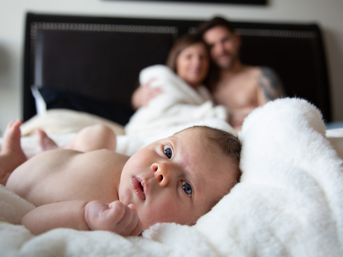Peaceful baby on bed with man and woman, exuding comfort and guardianship